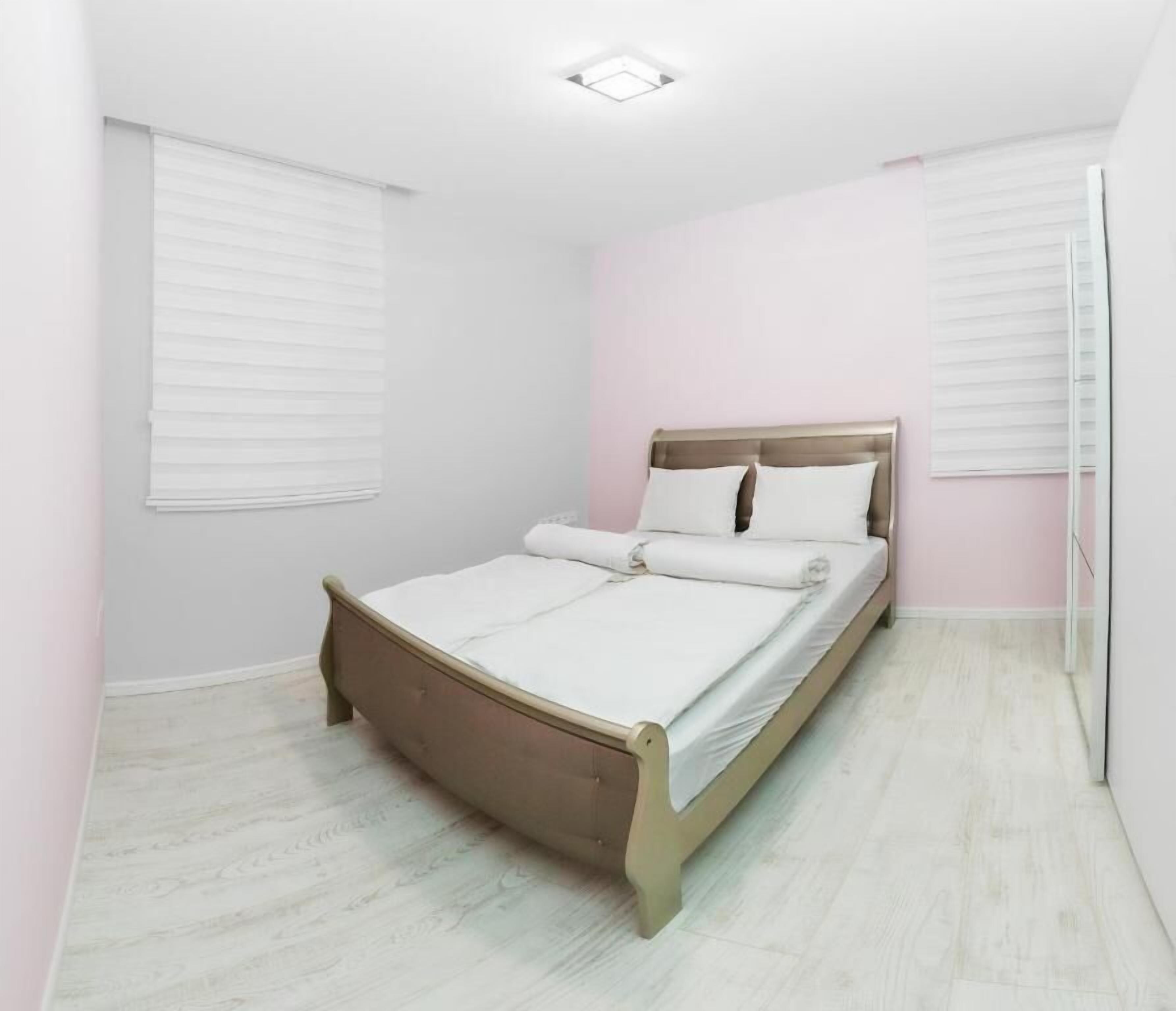 Un dormitorio con cama, paredes blancas y suelo de color claro.