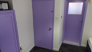 Un couloir avec des portes violettes, un mur blanc et un sol carrelé.