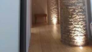 Un pasillo con un pilar de piedra, vigas de madera y un banco.