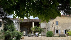 Un patio con un edificio rústico, una zona cubierta y mesas al aire libre.