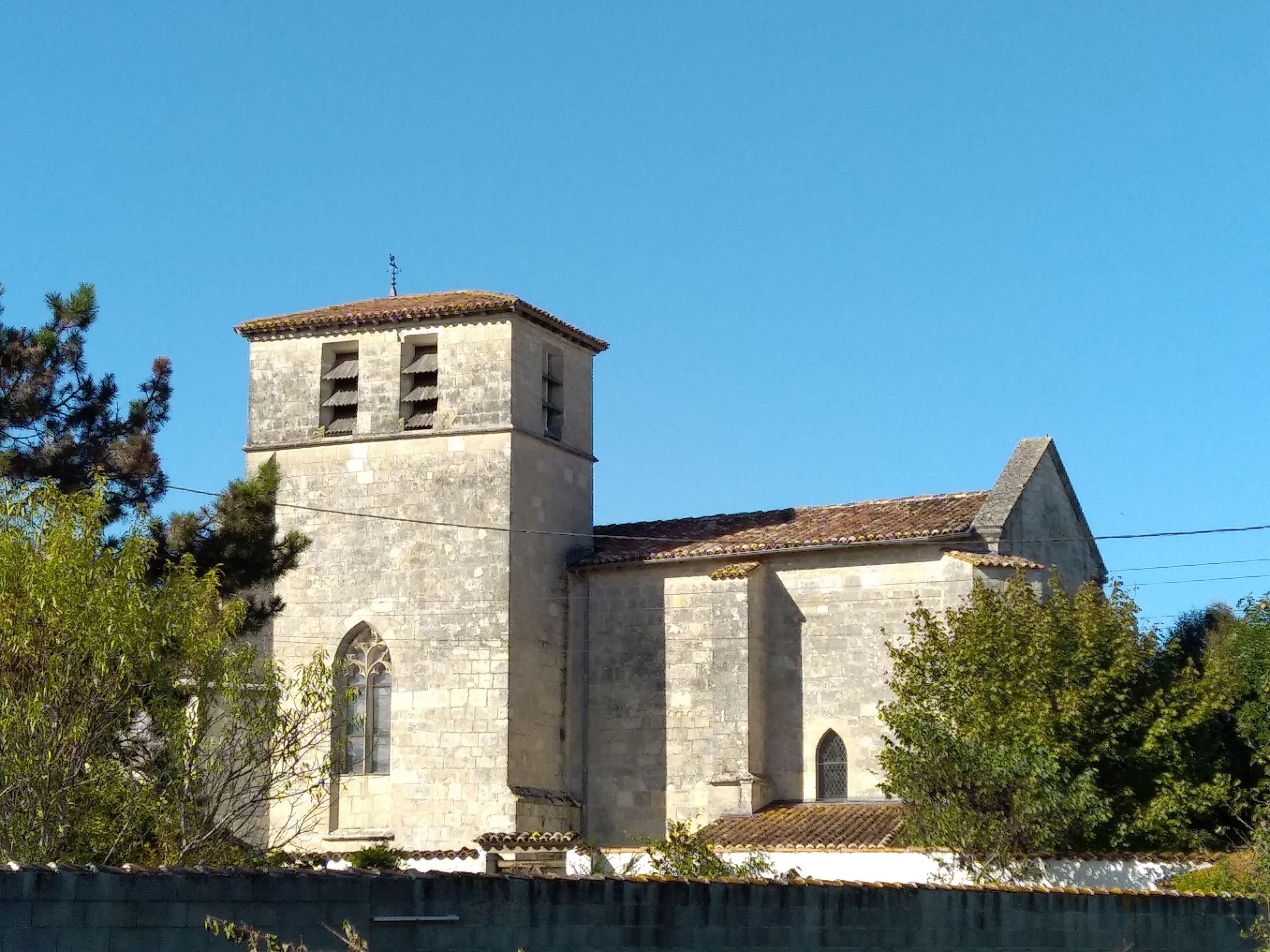 Una iglesia histórica de piedra con un campanario y ventanas de arco.