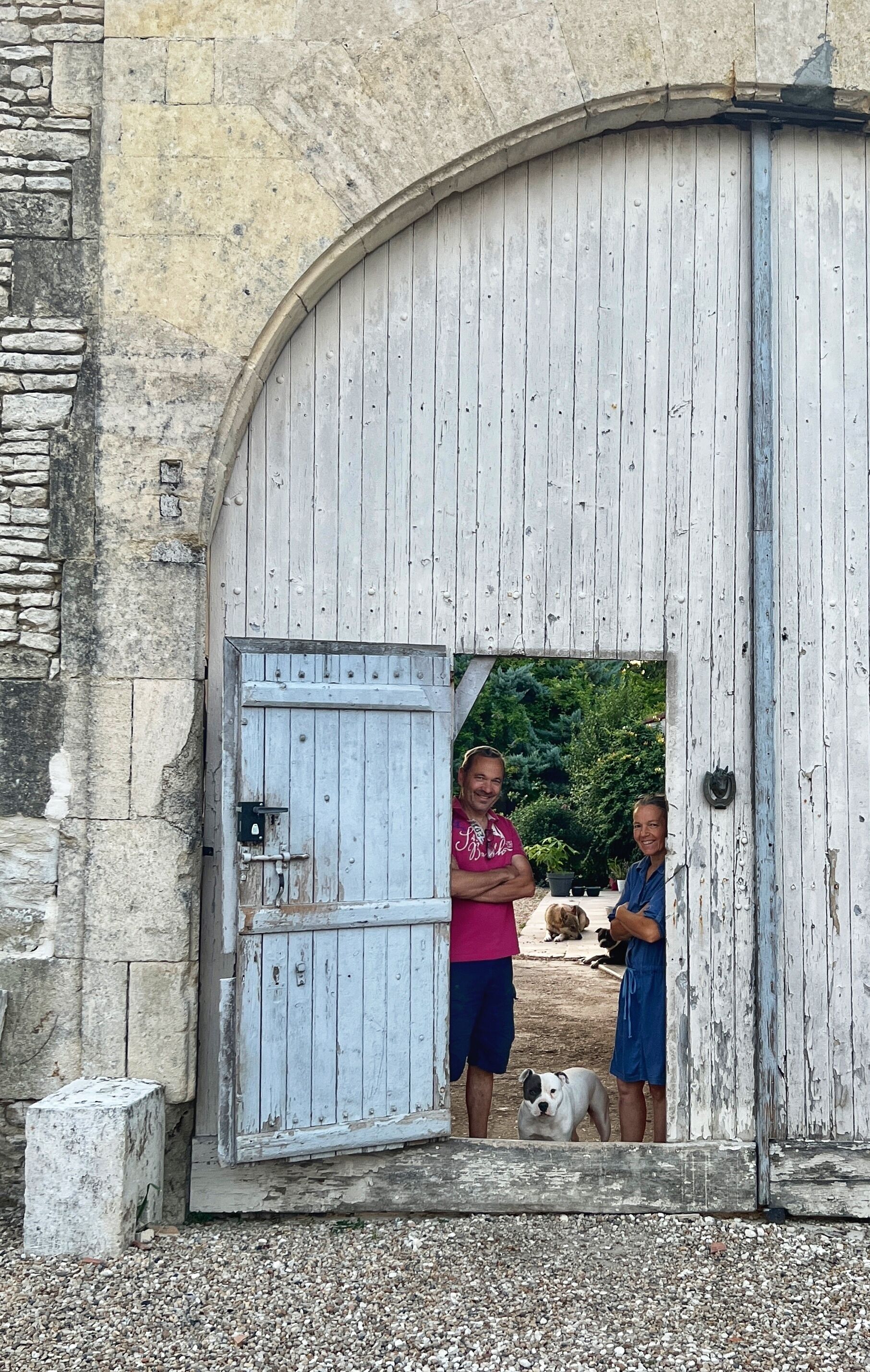 Uma porta de madeira rústica com uma parede de pedra e um pequeno cão em frente.