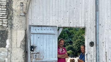 Uma porta de madeira rústica com uma parede de pedra e um pequeno cão em frente.
