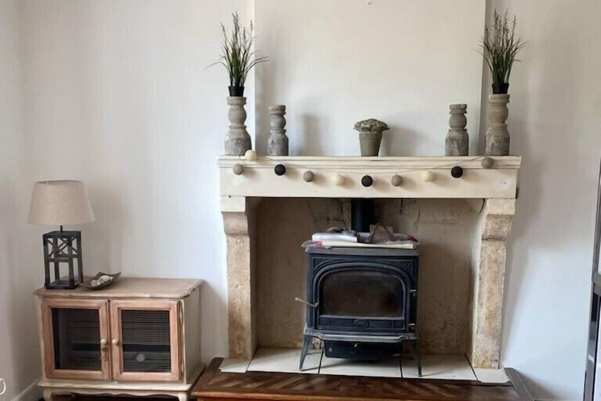 Una habitación con chimenea, un banco de madera y un aparador con una lámpara.