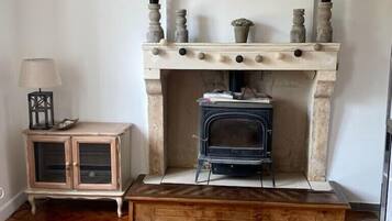 A room with a fireplace, a wooden bench, and a cabinet with a lamp.