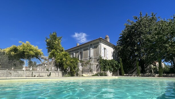 Una piscina cristalina con un edificio al fondo.