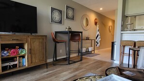 A living room with a television, wooden cabinet, and a dining area with chairs. - Ground Floor Waterfront Condo! (Montgomery)
