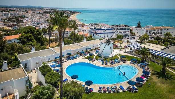 Un complexe hôtelier doté d’une grande piscine, offrant une vue sur la plage et comprenant un moulin à vent.