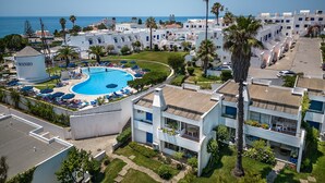 Un complexe hôtelier doté d’une piscine, de plusieurs bâtiments et offrant une vue sur la mer.