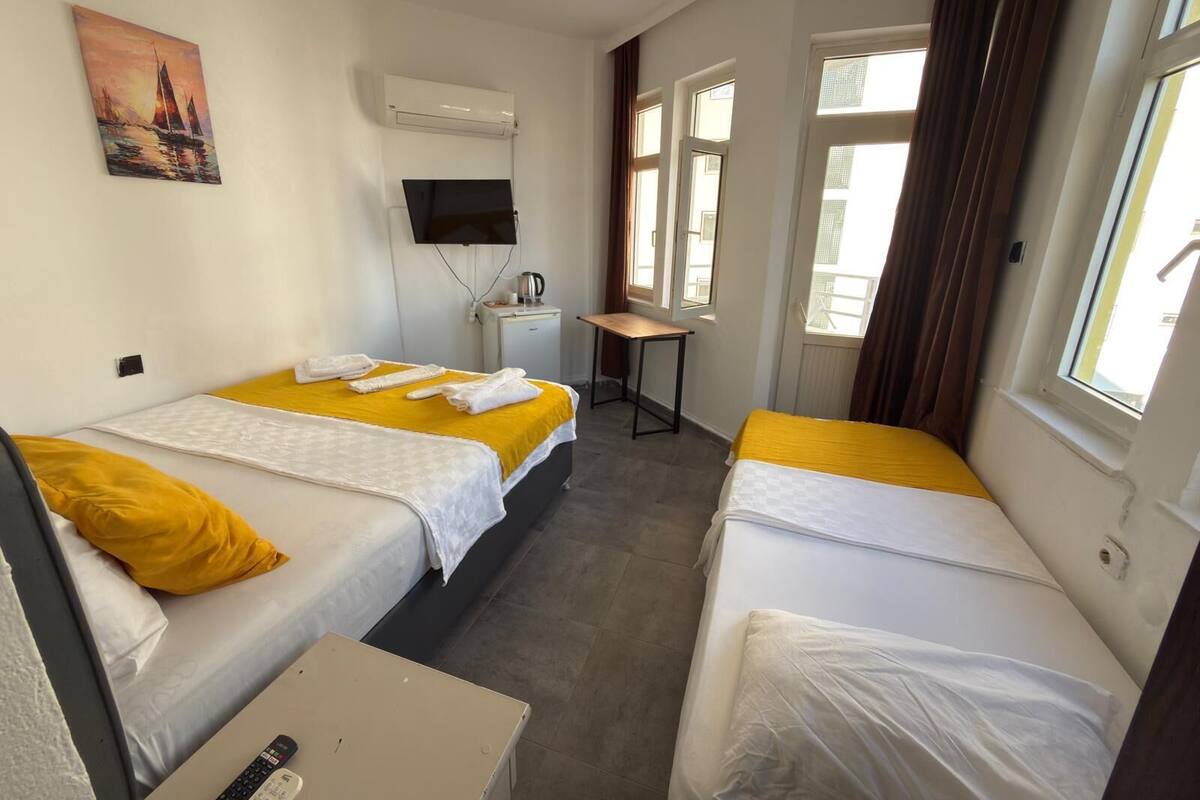 A hotel room with two beds, a desk, a TV, and a painting on the wall.