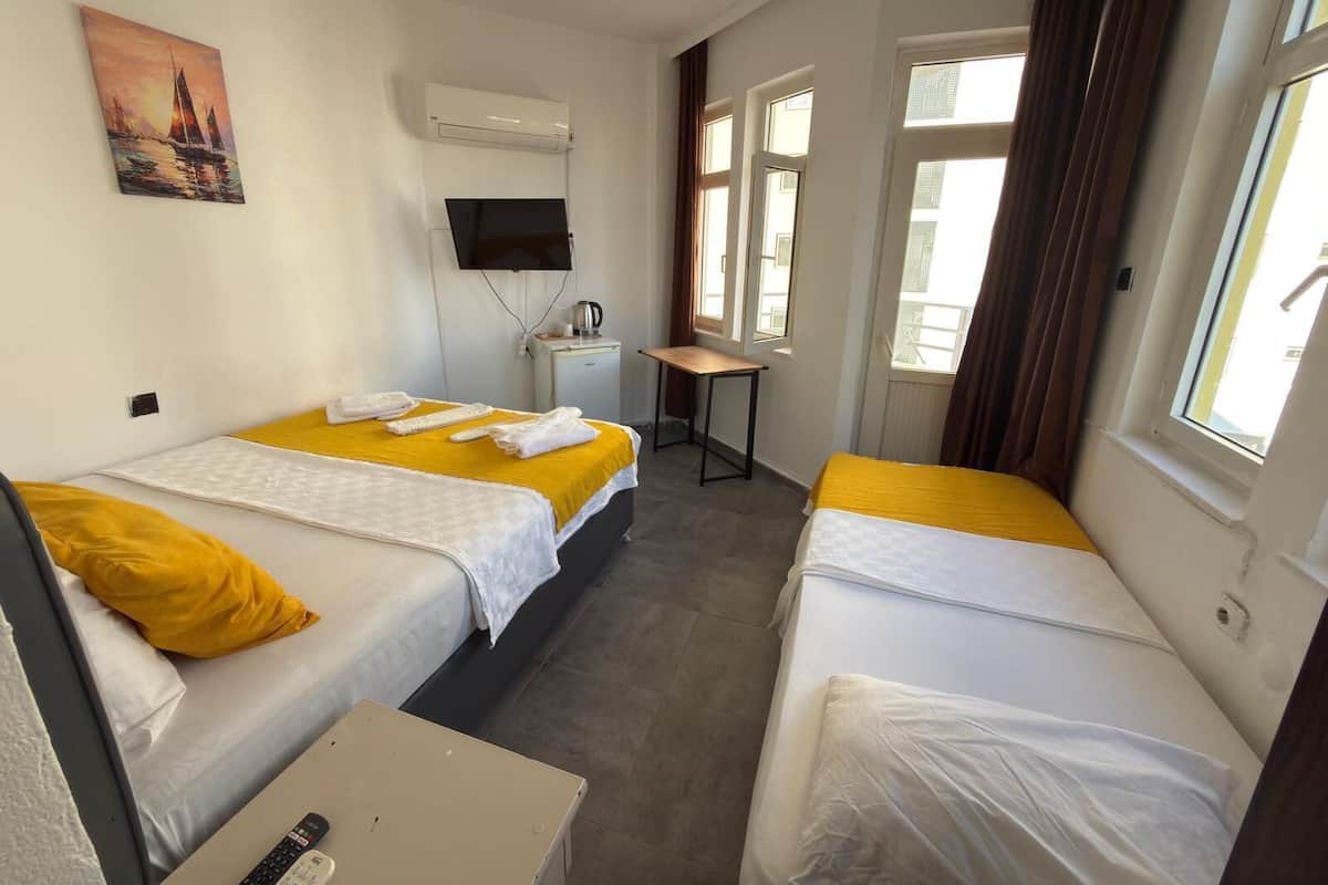 A hotel room with two beds, a desk, a TV, and a painting on the wall.
