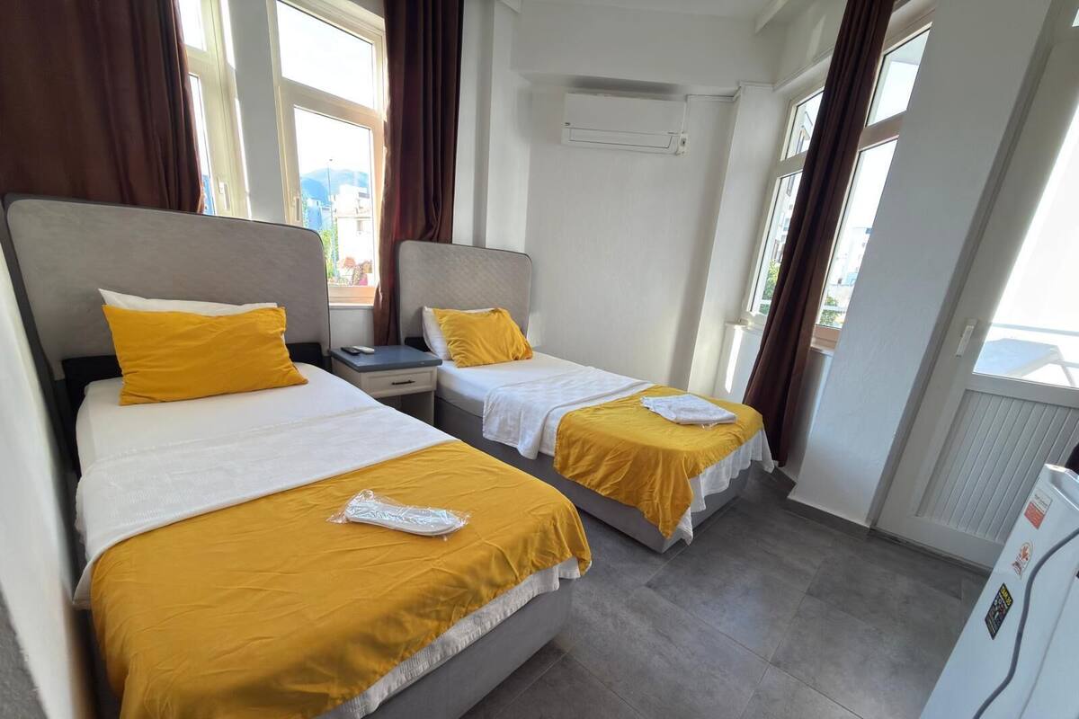 A hotel room with two beds, a nightstand, a window, and an air conditioning unit.
