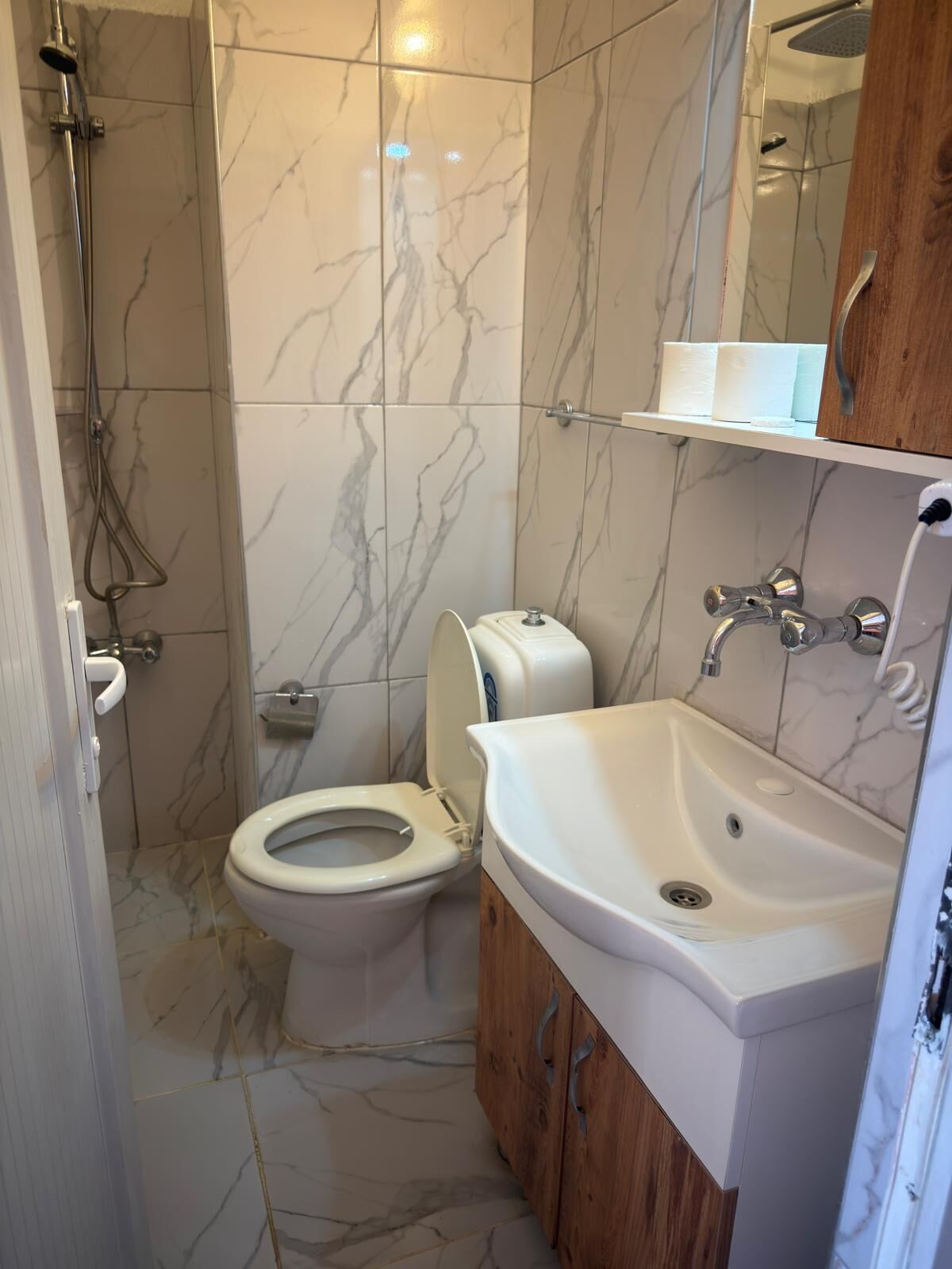A bathroom with a toilet, sink, and shower.