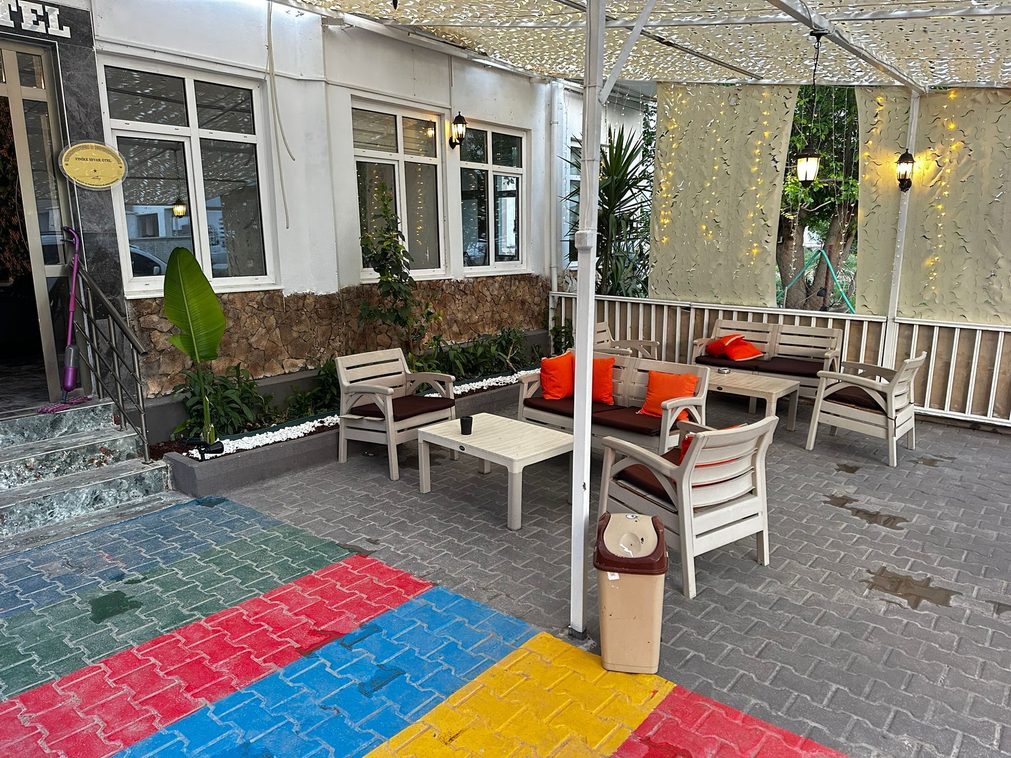 A hotel patio with outdoor seating, a stone wall, and a sign indicating the hotel name.
