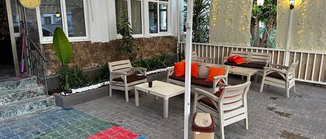 A hotel patio with outdoor seating, a stone wall, and a sign indicating the hotel name.