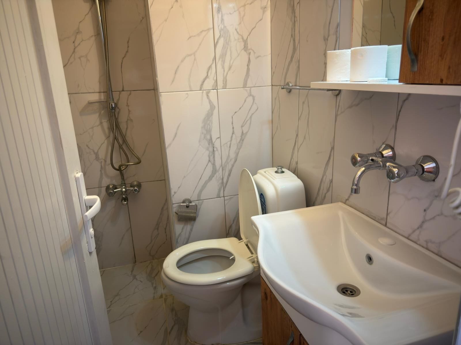 A bathroom with a toilet, shower, and sink.