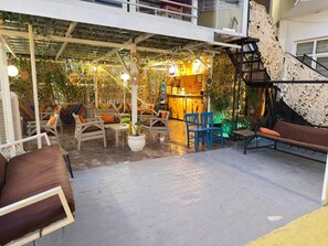 Un espace extérieur abrité, aménagé avec des tables et des chaises, un coin bar et un escalier.