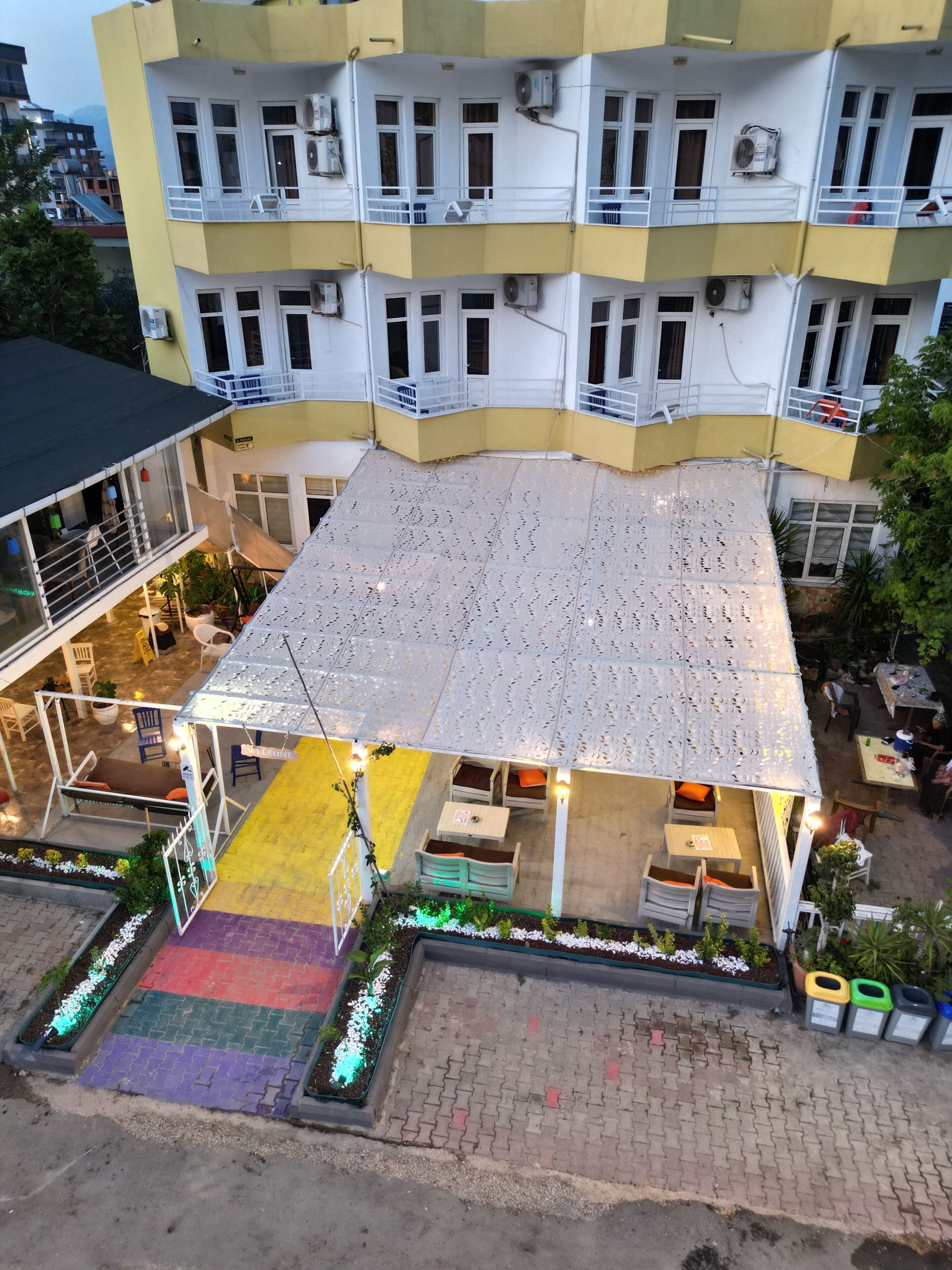 A multi-story building with balconies, outdoor seating, and air conditioning units.