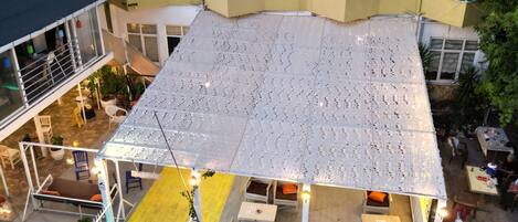 A multi-story building with balconies, outdoor seating, and air conditioning units.