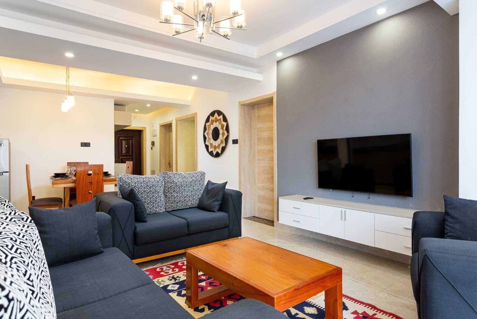 Un salon moderne avec un canapé, une table basse et un téléviseur posé sur un meuble blanc.