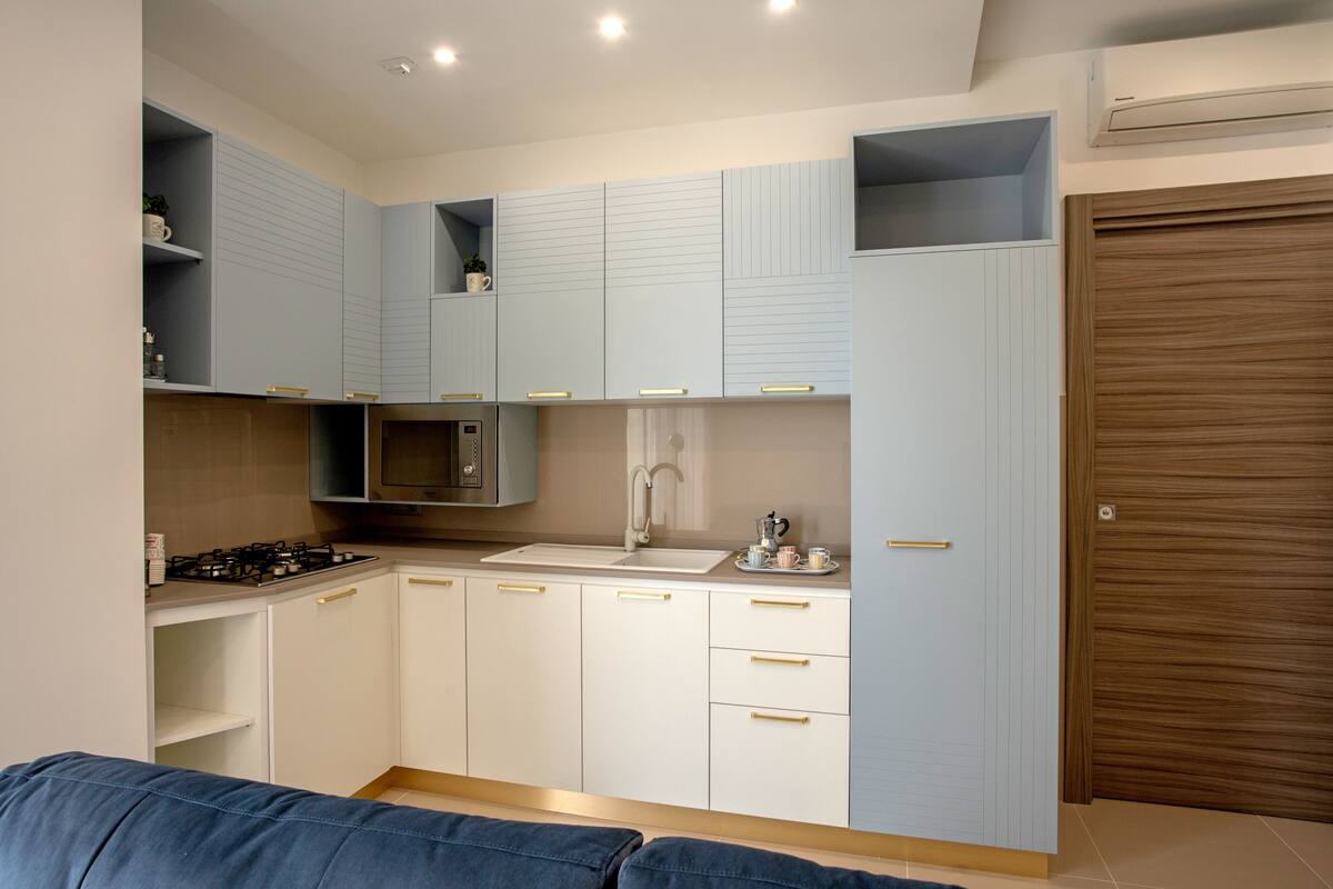 Une cuisine moderne avec des meubles blancs, une cuisinière à gaz, un four à micro-ondes et un évier.