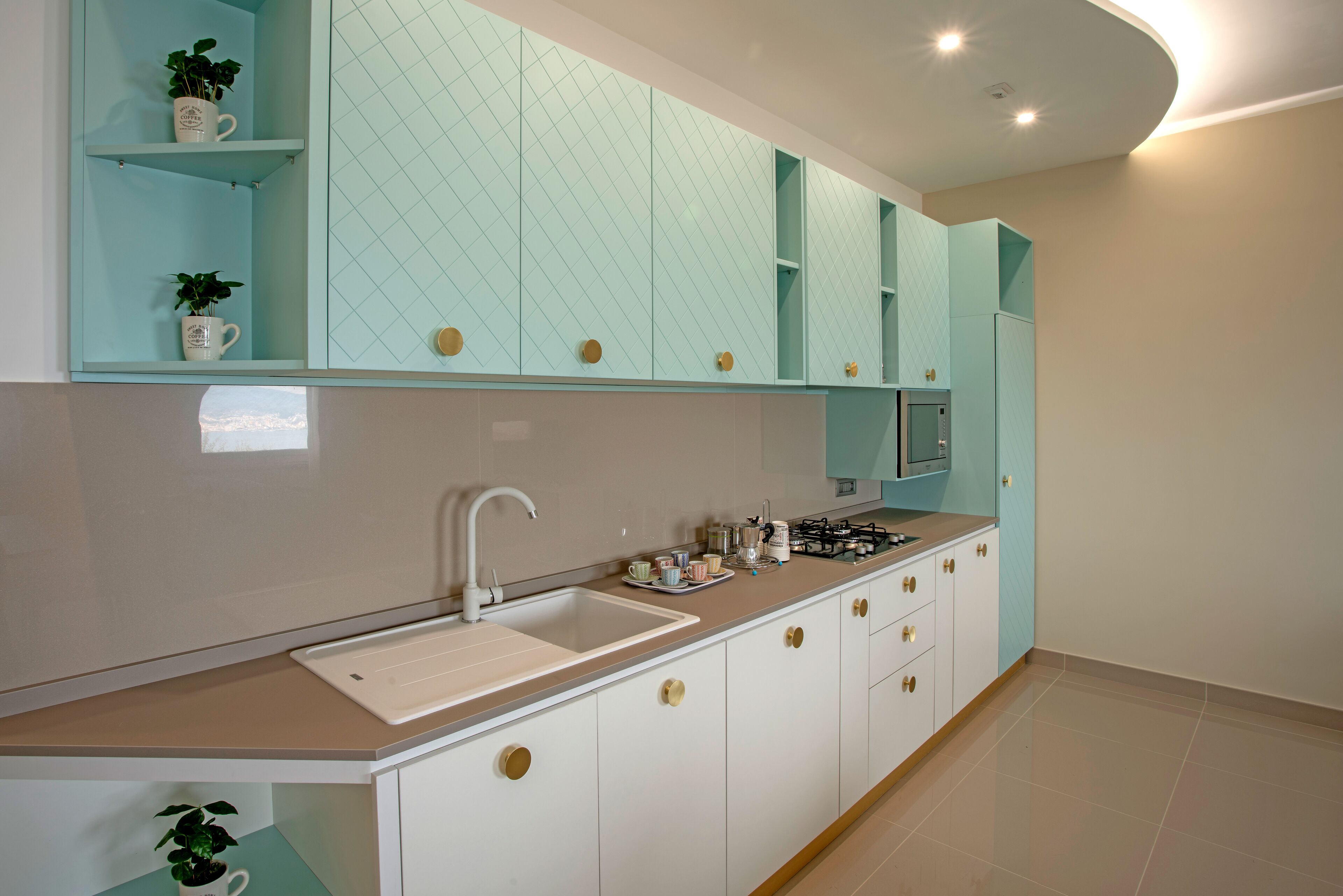 Une cuisine moderne avec des meubles blancs, un plan de travail beige et une cuisinière à gaz intégrée.