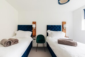 A hotel room with two beds, a green chair, and a wooden headboard.