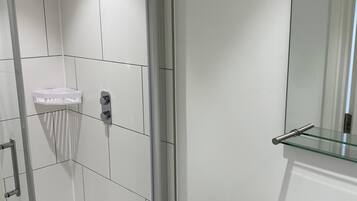 Une salle de bain moderne avec une douche à parois de verre, un lavabo blanc et un miroir au-dessus du lavabo.