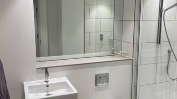 A modern bathroom with a white sink, toilet, and glass shower enclosure.