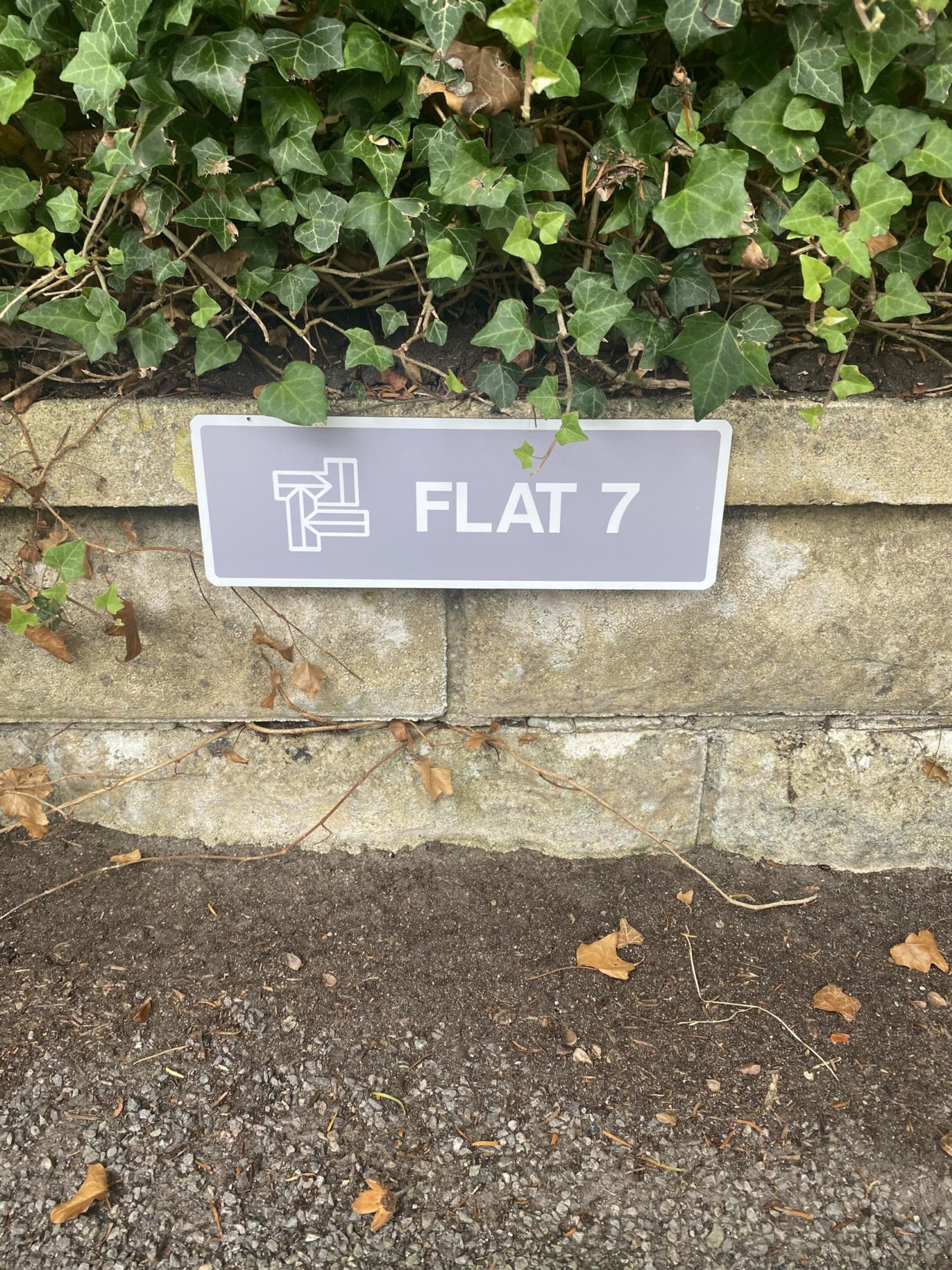 Una señal de calle con el texto 'FLAT 7' y un símbolo que indica un apartamento.