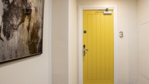 Een gele deur met het cijfer '3' op de muur ernaast.
