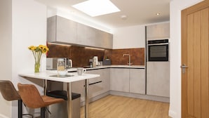 Een moderne keuken met een wit aanrecht, roestvrijstalen apparatuur en een houten deur.