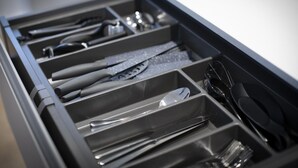 Un cajón con divisiones que contiene diversos utensilios de cocina.