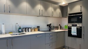 Una cocina moderna con armarios grises, un lavamanos de acero inoxidable y un horno Bosch.