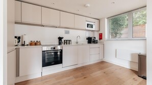 A modern kitchen with white cabinetry, a Bosch oven, and a window with blinds. - CH Apt 4 2bed in Bath (Bath)