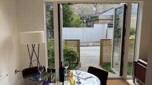 A dining area with a glass table and chairs, a bottle of wine, and a lamp. - CH Apt 4 2bed in Bath (Bath)