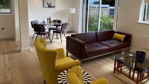 A modern living room with a leather sofa, yellow armchairs, and a glass coffee table. - CH Apt 4 2bed in Bath (Bath)