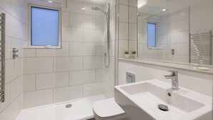 Une salle de bain moderne avec une douche à l’italienne, des toilettes et un lavabo.