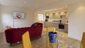 Un salon moderne avec un canapé rouge, un fauteuil jaune et une table en verre sur laquelle se trouvent un seau à champagne et des verres.