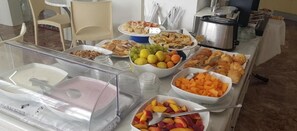 A buffet table with various food items including fruits, pastries, and a hot beverage station. - Hotel Haiti B&B (Cervia)