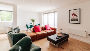 A modern living room with a leather sofa, green chairs, a coffee table, and a framed artwork on the wall. - CH Apt 5 2bed in Bath (Bath)