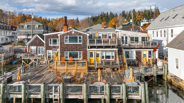 A waterfront property with multiple buildings, wooden docks, and outdoor seating areas. - The Angelique - Inn on the Harbor (Stonington)