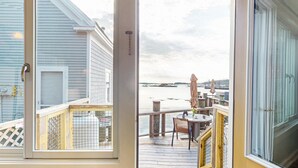 A deck with a table and chairs, overlooking a body of water with boats. - The Angelique - Inn on the Harbor (Stonington)