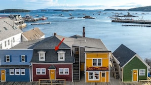 A waterfront hotel with a dock, a staircase leading to the upper level, and a view of boats in the water. - The Grace Bailey - Inn on the Harbor (Stonington)