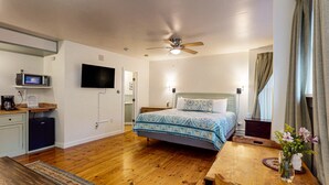 A bedroom with a bed, a desk, a television, and a ceiling fan. - The Isaac Evans - Inn on the Harbor (Stonington)