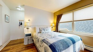 A bedroom with a bed, bedside lamps, a nightstand, a window with blinds, and a picture on the wall. - The Nathaniel Bowditch - Inn on the Harbor (Stonington)