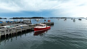 Un puerto con barcos amarrados a muelles de madera, agua tranquila y una costa lejana.