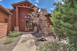 A wooden house with a stone entrance, a small garden with a tree, and a clear sky. - Golf Course & Lake Views: Luxe Show Low Cabin (Show Low)