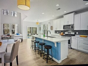 Enjoy cooking in this well-equipped kitchen with a central island, sink, and bar stools.