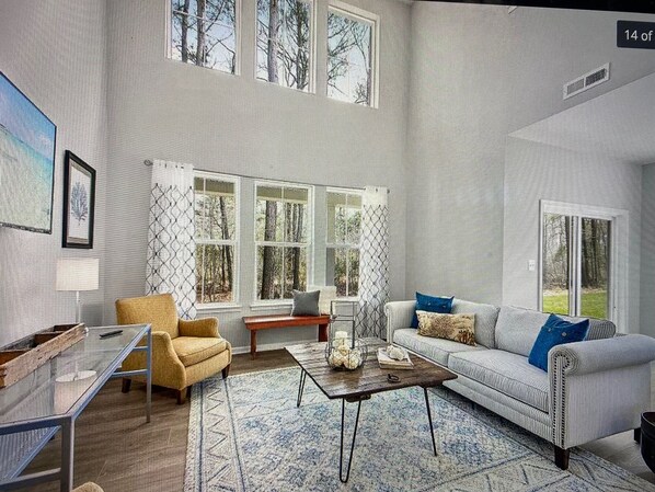 Relax in a spacious living room with high ceilings and large windows offering a view of the outdoors.